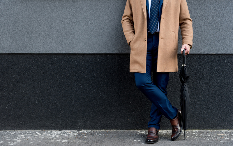 cropped view of businessman holding umbrella, in peacoat over suit