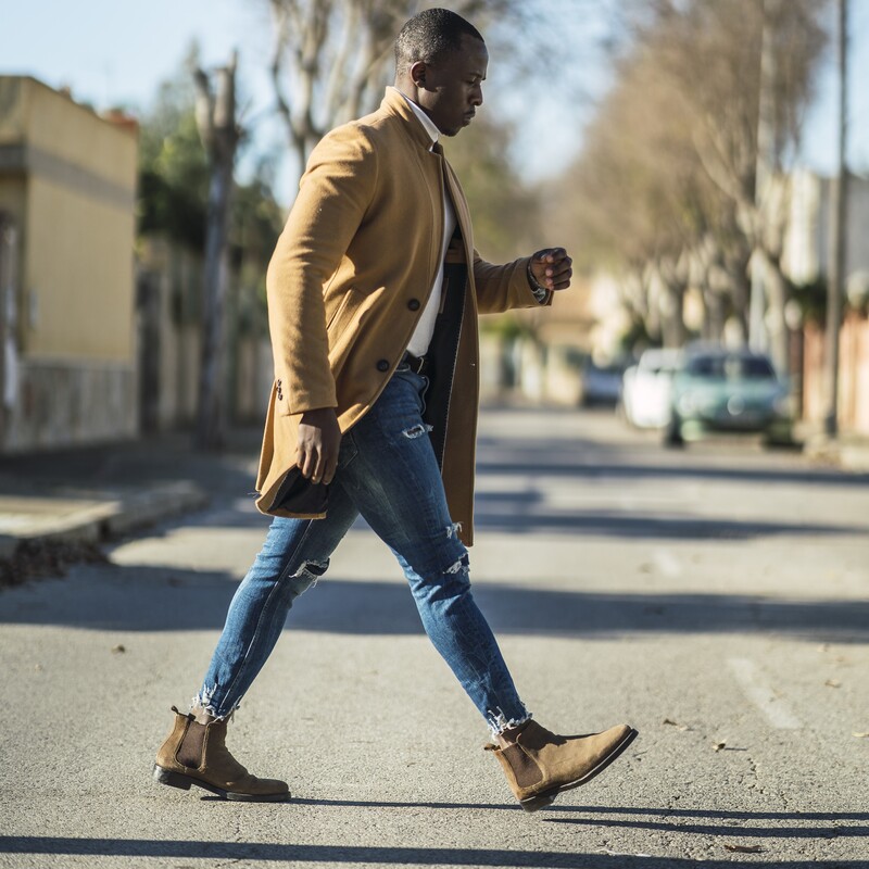 a stylish african man walking on the streets on chelsea boots