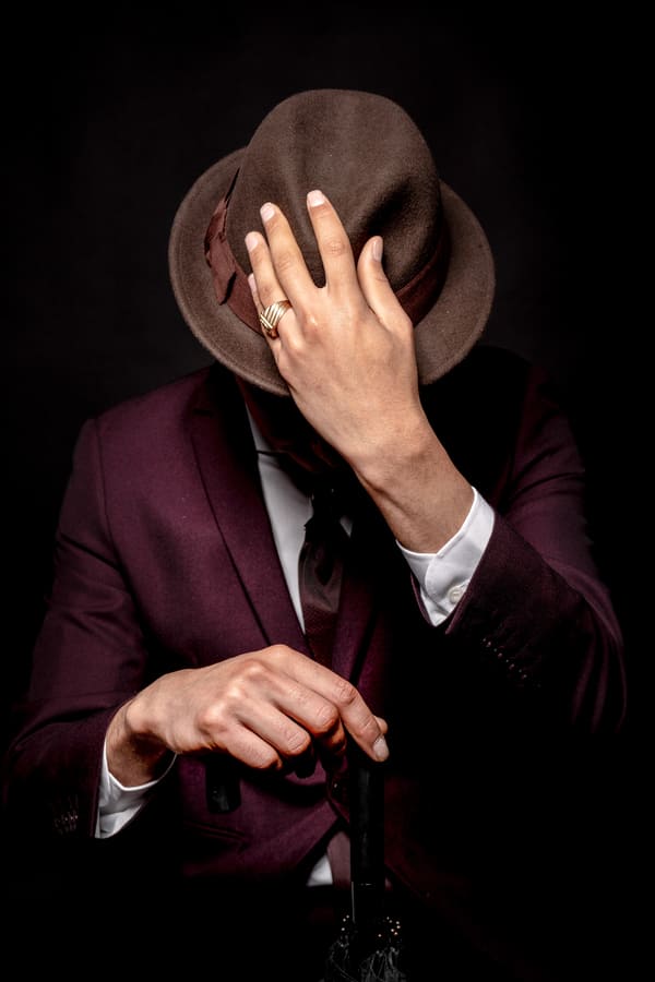 man in suit on fedora hat in black background